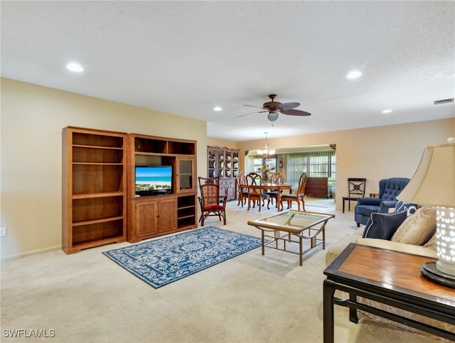 carpeted living room with a textured ceiling and ceiling fan with notable chandelier