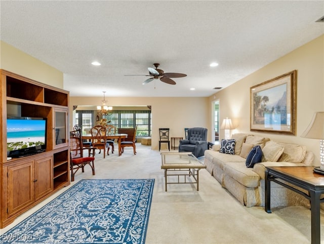 carpeted living room with a textured ceiling and ceiling fan with notable chandelier