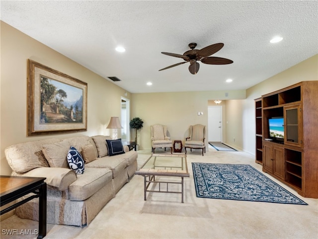 living room featuring a textured ceiling, light colored carpet, and ceiling fan