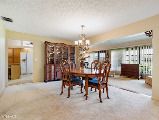 dining space with a textured ceiling, light carpet, and a notable chandelier