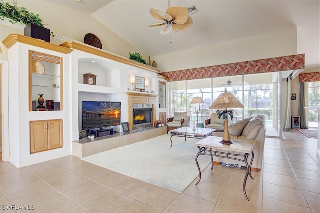 living room featuring light tile patterned floors, a tiled fireplace, ceiling fan, and built in shelves