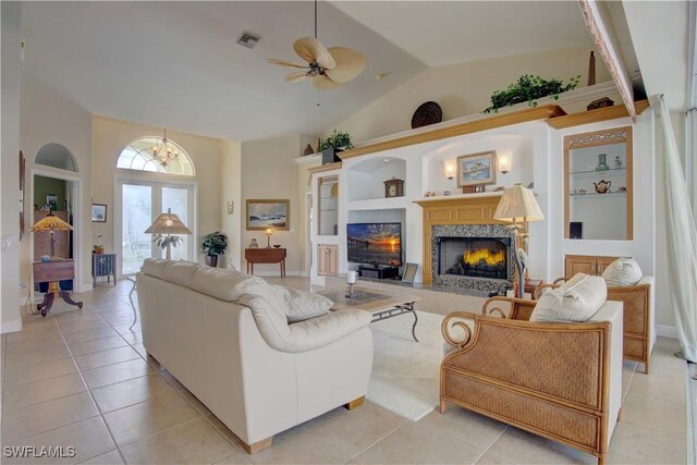 tiled living room with ceiling fan, vaulted ceiling, and built in features