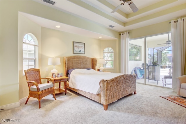 bedroom with ceiling fan, light carpet, access to outside, and a tray ceiling