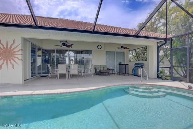 view of swimming pool with glass enclosure, a patio, and ceiling fan