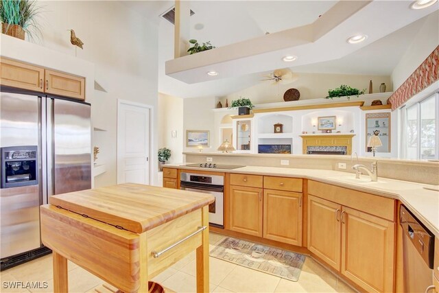 kitchen featuring ceiling fan, high vaulted ceiling, light tile patterned floors, sink, and stainless steel appliances