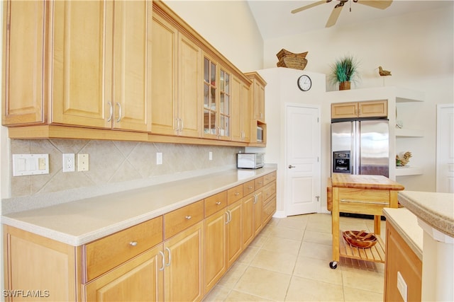 kitchen featuring ceiling fan, decorative backsplash, vaulted ceiling, light tile patterned floors, and stainless steel fridge with ice dispenser