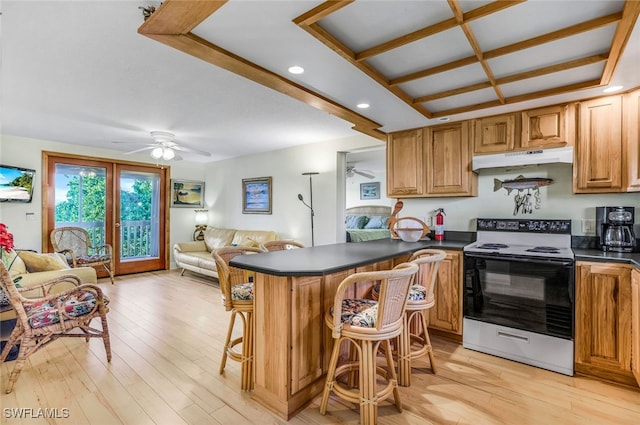 kitchen featuring electric stove, dark countertops, a peninsula, under cabinet range hood, and a kitchen bar