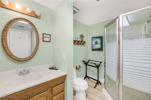 bathroom with toilet, a stall shower, wood finished floors, and vanity