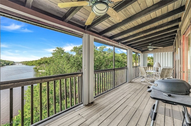 deck with ceiling fan, grilling area, and a water view