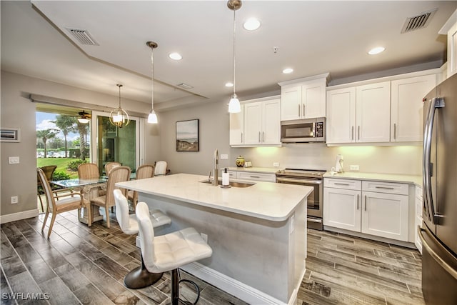 kitchen with decorative light fixtures, white cabinetry, appliances with stainless steel finishes, and sink