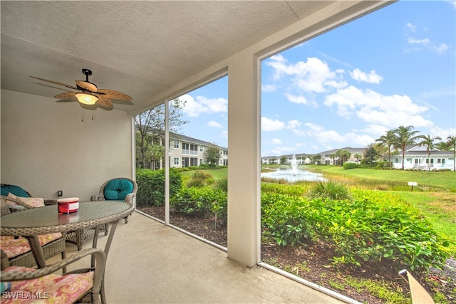 sunroom / solarium featuring ceiling fan and a water view