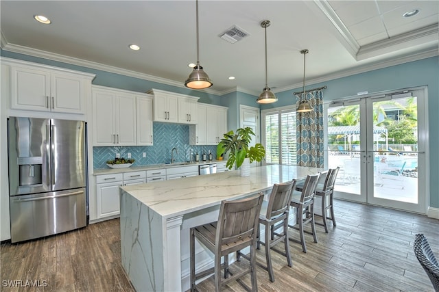 kitchen featuring white cabinetry, light stone counters, stainless steel fridge, and plenty of natural light