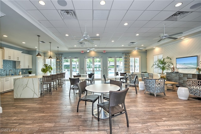 dining room with hardwood / wood-style flooring, ceiling fan, sink, and ornamental molding