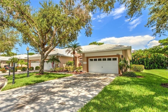 single story home with a garage, a front yard, concrete driveway, and stucco siding