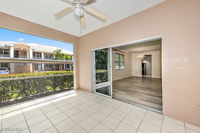 unfurnished sunroom with ceiling fan with notable chandelier