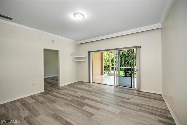 spare room featuring light wood-type flooring, visible vents, crown molding, and baseboards