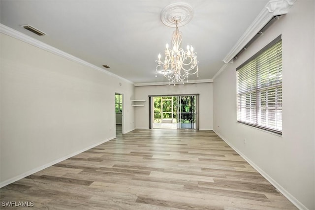 spare room with light wood finished floors, ornamental molding, a chandelier, and visible vents