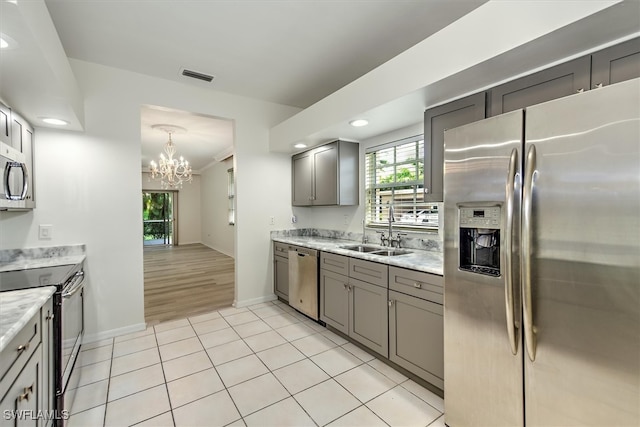 kitchen featuring light hardwood / wood-style flooring, a chandelier, gray cabinets, appliances with stainless steel finishes, and sink