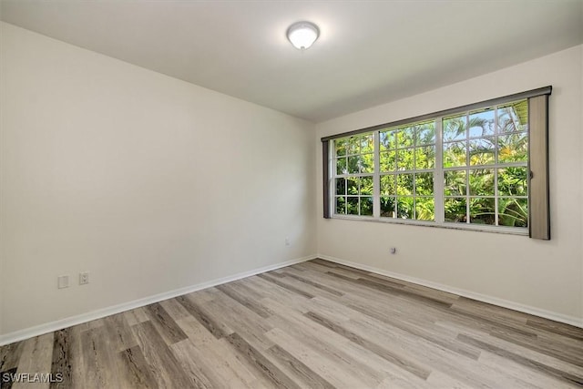 spare room with baseboards and light wood finished floors