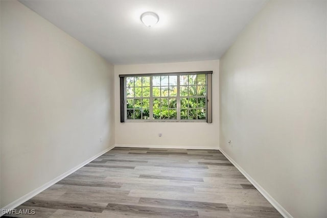 unfurnished room with baseboards and light wood finished floors