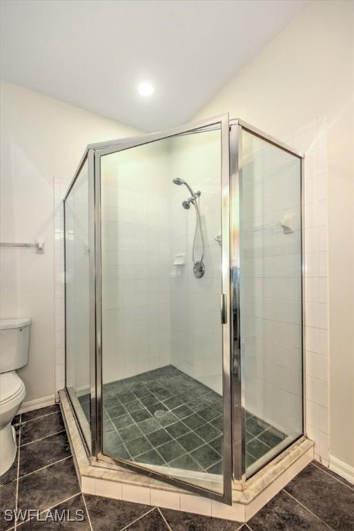 full bathroom featuring toilet, a stall shower, tile patterned flooring, and baseboards