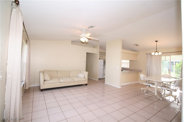 tiled living room featuring lofted ceiling and ceiling fan with notable chandelier