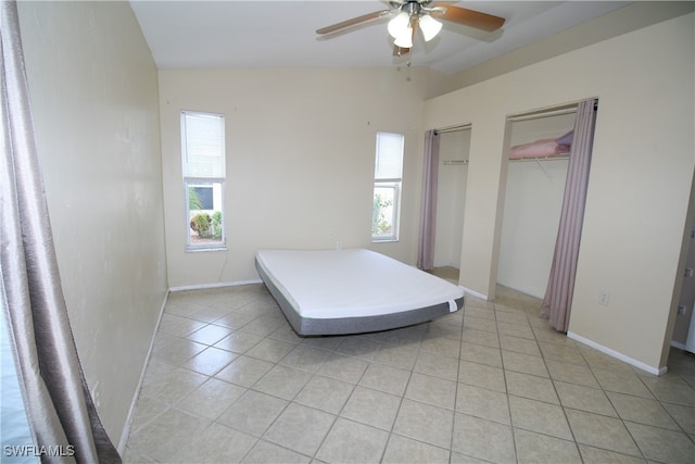 tiled bedroom with vaulted ceiling, two closets, and ceiling fan