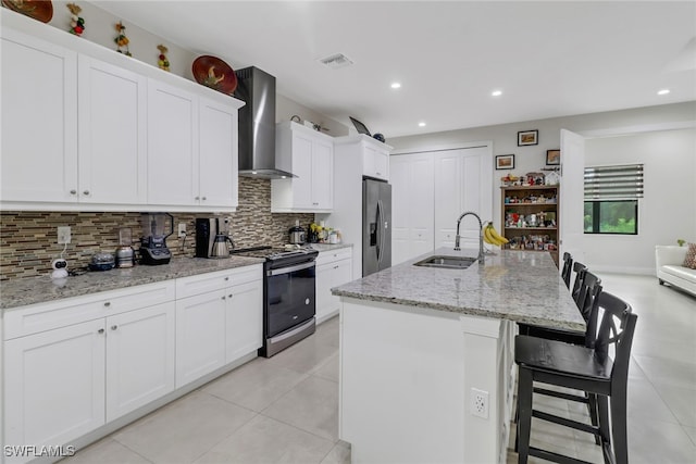 kitchen featuring wall chimney range hood, tasteful backsplash, appliances with stainless steel finishes, sink, and light tile patterned flooring