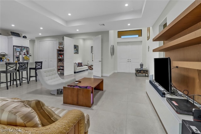 living room featuring a tray ceiling and light tile patterned flooring