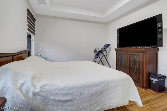 bedroom featuring a raised ceiling and light hardwood / wood-style flooring