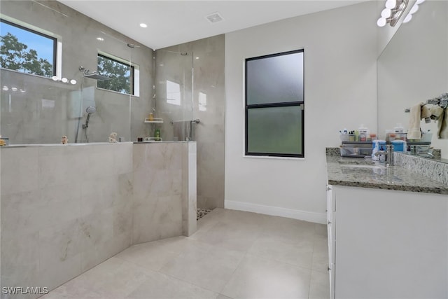 bathroom featuring tile patterned floors, a tile shower, and vanity