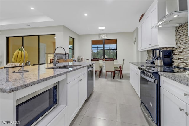 kitchen with backsplash, sink, black microwave, electric range, and wall chimney range hood