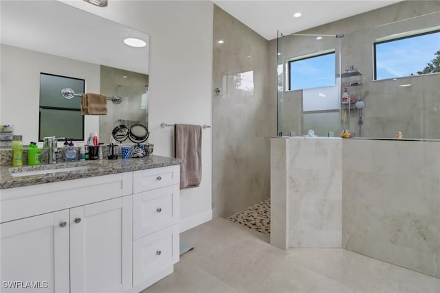 bathroom featuring a tile shower, vanity, and tile patterned floors