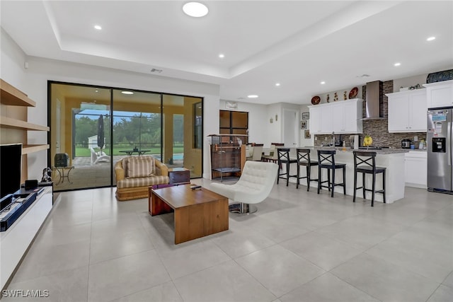 living room with a tray ceiling and light tile patterned flooring