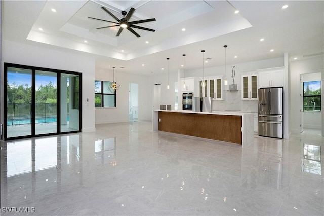 3660 4th Ave NE, Naples, FL 34120 - kitchen with ceiling fan, stainless steel appliances, white cabinetry, open floor plan, and a tray ceiling