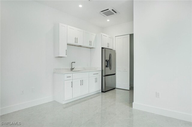 kitchen featuring sink, white cabinets, light tile patterned floors, and stainless steel refrigerator with ice dispenser