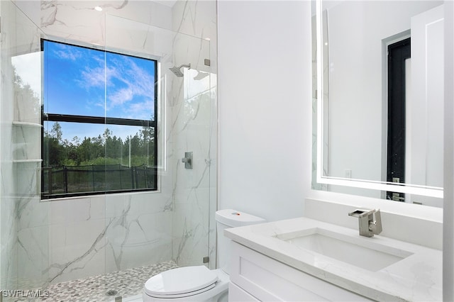 bathroom featuring a shower with shower door, toilet, and vanity