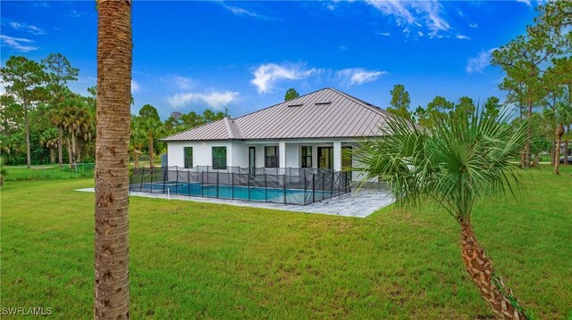 rear view of property featuring a lawn and a fenced in pool