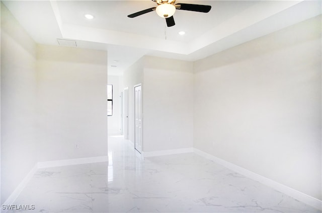 unfurnished room featuring a raised ceiling and ceiling fan