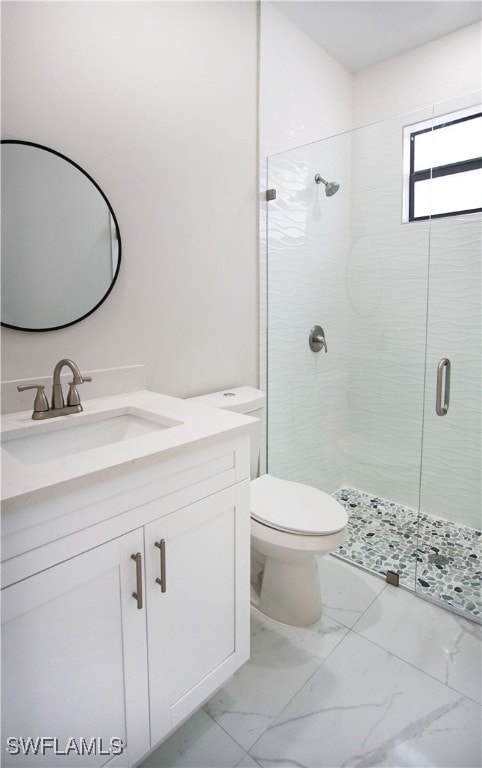 bathroom featuring vanity, toilet, and a shower with door