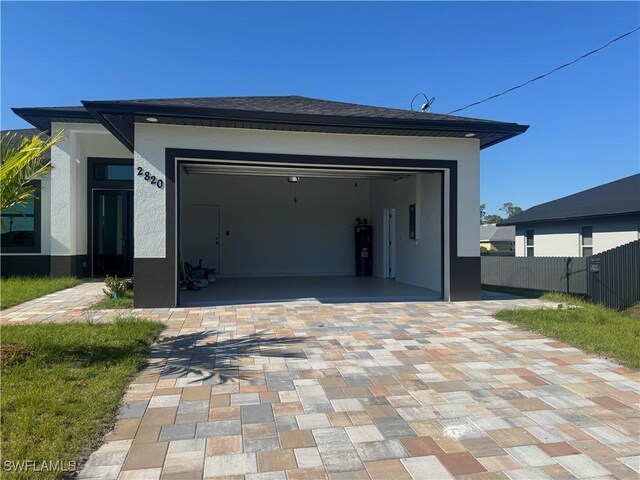 garage featuring fence and decorative driveway
