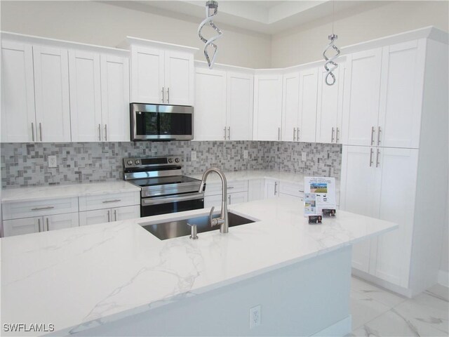 kitchen featuring light stone counters, a sink, white cabinets, and stainless steel appliances