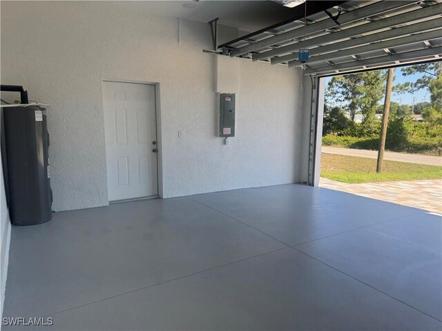 garage featuring a textured wall, electric panel, and water heater