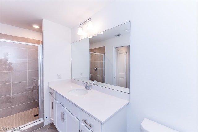 bathroom with tile patterned flooring, toilet, vanity, and a shower with shower door