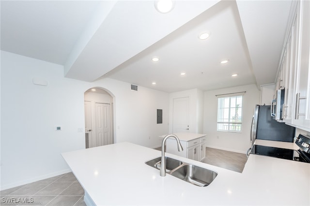 kitchen with sink, stainless steel appliances, white cabinetry, and light tile patterned floors