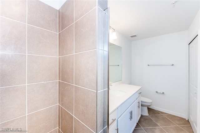 bathroom featuring tile patterned flooring, toilet, vanity, and tiled shower