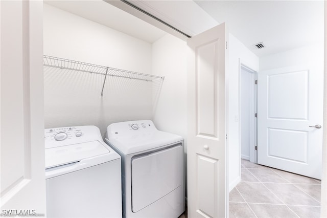 laundry room with washing machine and clothes dryer and light tile patterned floors