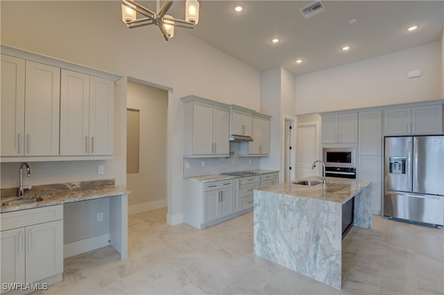 kitchen with high vaulted ceiling, stainless steel appliances, sink, and an island with sink