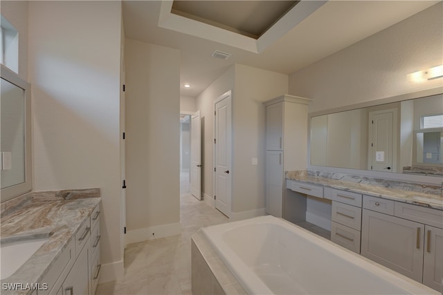 bathroom with vanity, tiled bath, and a raised ceiling