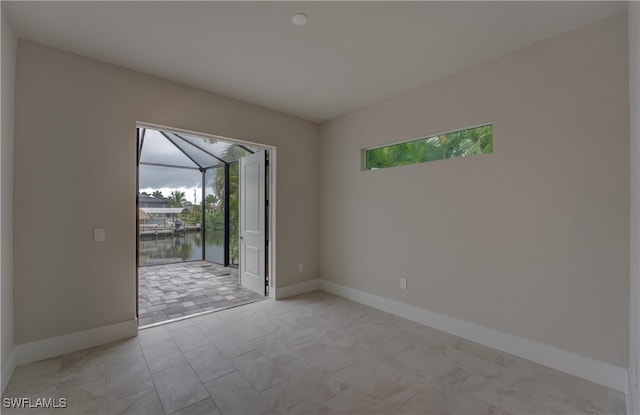 unfurnished room featuring a healthy amount of sunlight and a water view